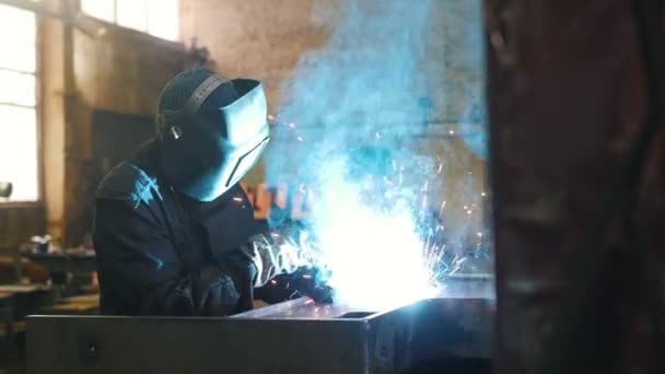 Εργοστάσιο κατασκευών. Ένας εργάτης σε κράνος με μηχανή συγκόλλησης. — Αρχείο Βίντεο
