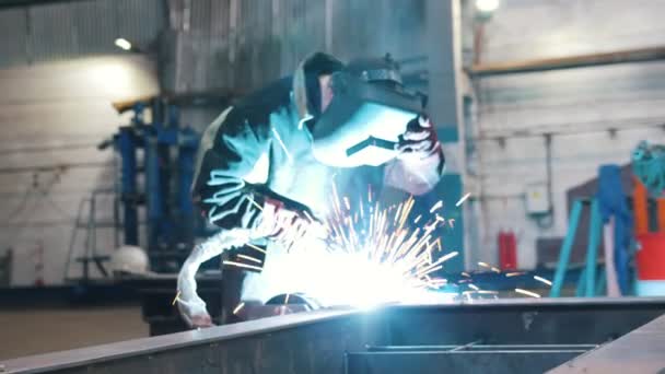 Fábrica de construção. Um homem trabalhador fechar um capacete e usando uma máquina de solda — Vídeo de Stock