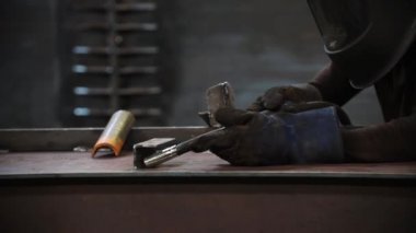 Koruyucu giysili bir adam kaynak makinesiyle çalışmaya başlar..
