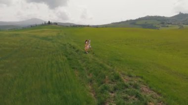 İki genç kadın tarlada etrafa bakar. İtalya, Toskana.
