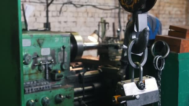 Concepto industrial. Construcción de plantas. Una cerradura colgando del gancho. Un anciano trabajando con un torno en el fondo — Vídeos de Stock