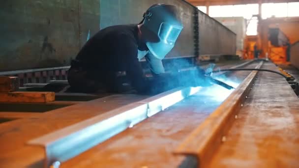 一个戴防护面具的男人在工厂的角落里焊接 — 图库视频影像