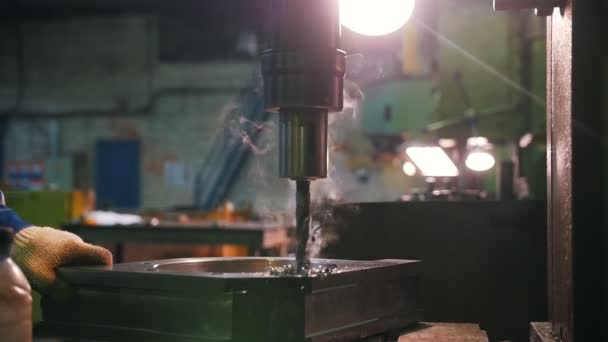 Un uomo conduce lavori di perforazione in parti metalliche. C'è del fumo. — Video Stock
