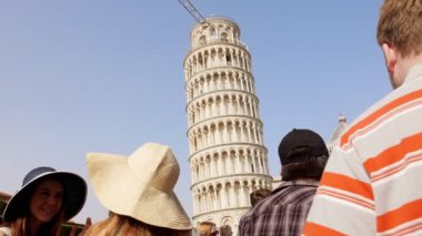 İtalya, Pisa. Pisa Kulesi 'nin önünde bir meydanda duran ve ona bakan iki genç kadın panamalar