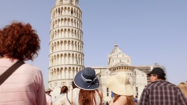 Italia, Pisa. Dua wanita muda di panama berdiri di alun-alun di depan Menara Pisa dan berbicara sambil memandangnya — Stok Video