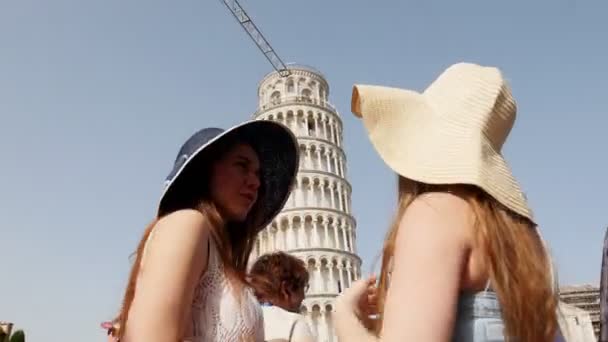 İtalya, Pisa. Pisa Kulesi 'nin önünde duran ve ona bakarken konuşan panamalar iki genç kadın — Stok video