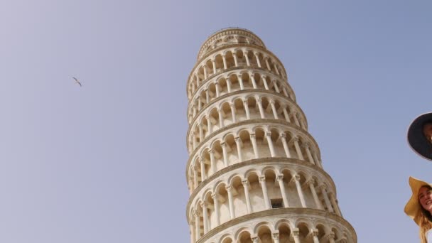 Italia, Pisa. Dos mujeres jóvenes en panamas caminando por la Torre Inclinada de Pisa y mirándola — Vídeo de stock