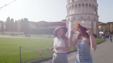 İtalya, Pisa. İki genç kadın parlak bir günde Pisa Kulesi bir arka planda yürüyüş