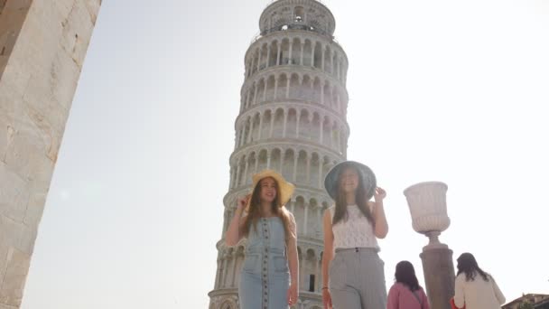 Italië, Pisa. Twee jonge vrouwen lopen op een achtergrond van de scheve toren van Pisa — Stockvideo