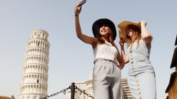 Ιταλία, Πίζα. Δύο νεαρές γυναίκες στα πανοράματα στέκονται σε ένα φόντο του Πύργου της Πίζας και παίρνοντας μια selfie — Αρχείο Βίντεο