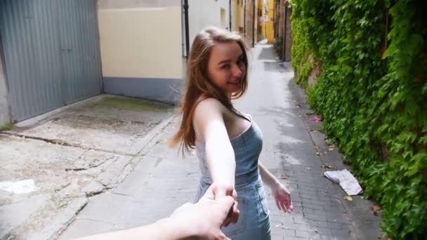 Eine junge hübsche Frau führt ihren Freund an der Hand durch eine Straße — Stockvideo