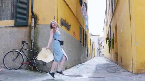 Две молодые путешествующие счастливые женщины ходят с багажом на фоне желтых стен — стоковое видео