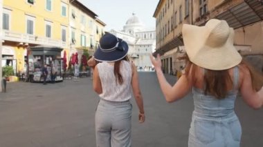 İtalya, Pisa. İki genç kadın sokaklarda panamalar yürüyüş