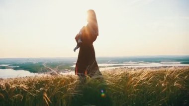 Genç bir anne bir buğday alanında bir bebek ile yürür