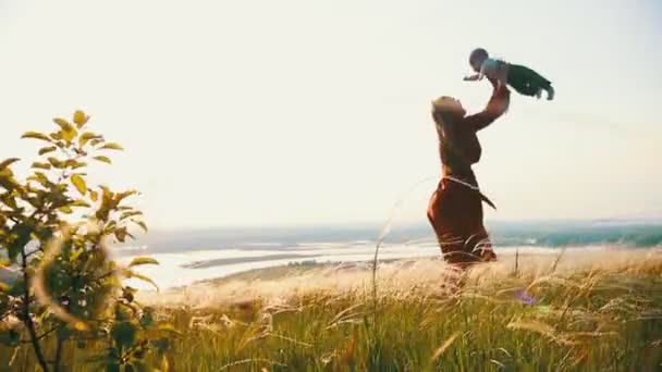 Jonge vrouw gooit baby in de zomer veld — Stockvideo
