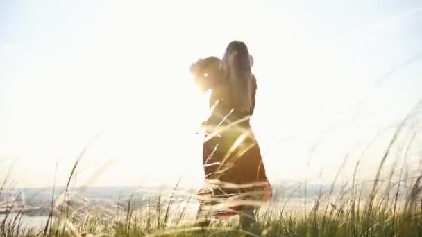En kvinna leker med ett barn. Spinning och leende. På bakgrunden av solnedgången himlen. — Stockvideo