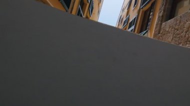 Sokakta binalar arasında alt gökyüzü görünümü. Kamera sokak boyunca hareket ediyor
