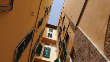 Binalar dar cadde görünümü. Kamera söner ve bir kadın görünür