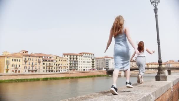 Две девушки бегут друг за другом по берегу реки. — стоковое видео