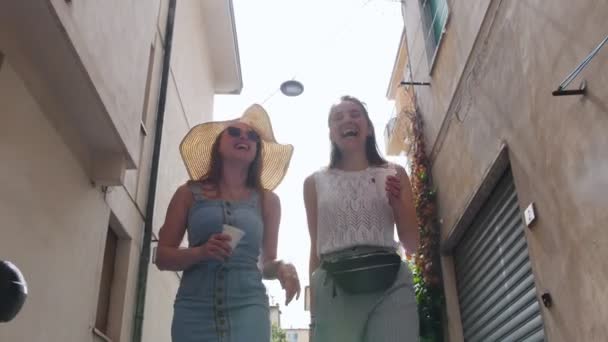 Twee jonge vrouwen lopen in de buurt van de gebouwen en lachen. — Stockvideo