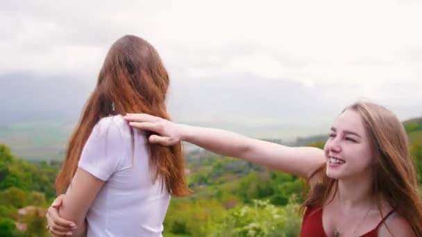 Zwei junge Frauen unterhalten sich und lachen. einer von ihnen zeigt dem anderen etwas und sie fangen an zu gehen — Stockvideo