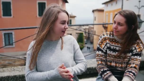 İki genç kadın oturan ve sokakta konuşuyor. — Stok video