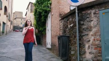 Genç bir kadın cadde boyunca ileriye doğru yürüyor. Sonra şehrin çatısından bir manzara göster.