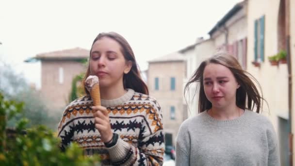 Молодая улыбающаяся женщина ест мороженое и другая женщина плачет и расстроена — стоковое видео