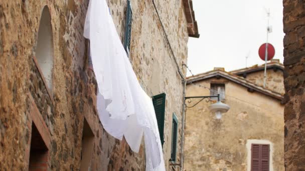 Ropa de cama en la secadora en un callejón estrecho en el fondo de los edificios antiguos — Vídeos de Stock