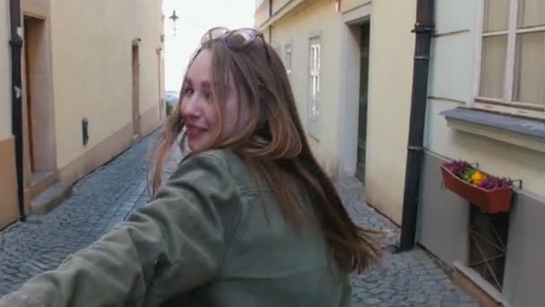 Uma jovem mulher sorrindo levando seu namorado jogar a rua à mão e enviar-lhe um beijo de sopro — Vídeo de Stock