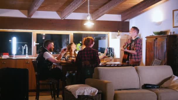 Un homme se tient à la table joue de la guitare et chante avec des amis — Video