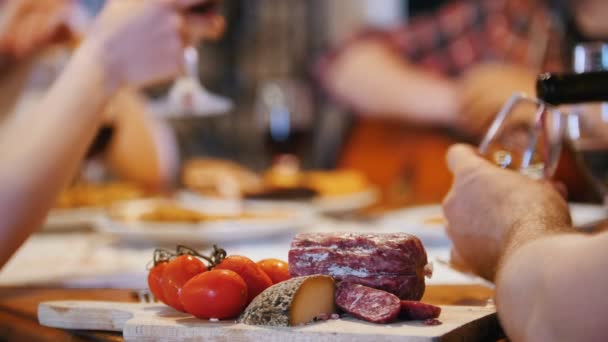 Des amis s'assoient à la table et clignent des verres - la saucisse est sur la table — Video