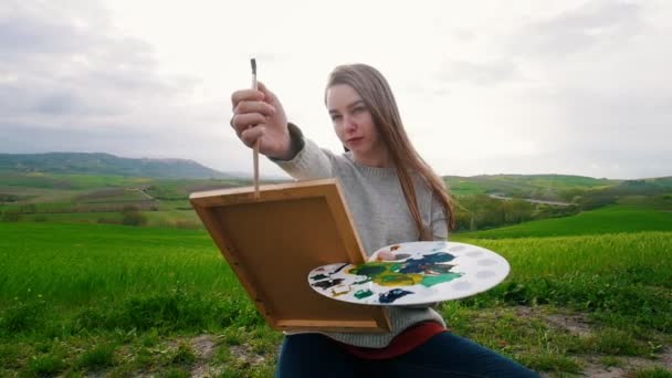 Une jeune femme talentueuse s'assoit sur le pré et dessine - Mesure les proportions de l'image — Video