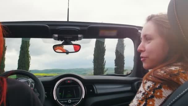 Twee jonge vrouwen rijden en een van hen tonen aan andere een buurt — Stockvideo