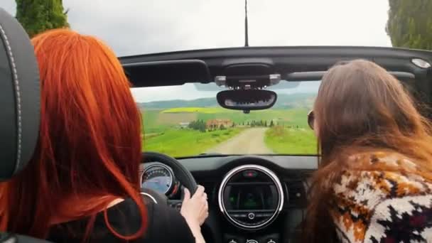 Twee jonge vrouwen gaan met de auto. Ze chatten en bladeren rond. — Stockvideo