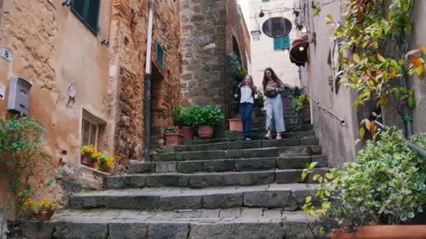 Две молодые женщины спускаются по лестнице с чашками в руках. . — стоковое видео