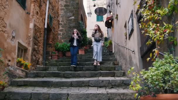 Dos mujeres jóvenes beben café hundiéndose por las escaleras — Vídeos de Stock