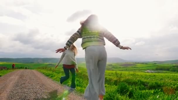 Dos mujeres atractivas corriendo y girando a través de un campo verde . — Vídeos de Stock