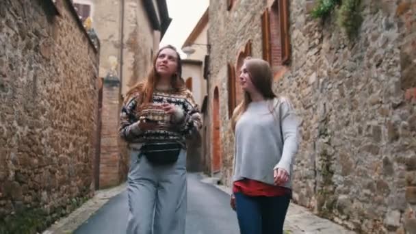 Молодые привлекательные женщины ходят по узким улочкам и делают селфи — стоковое видео