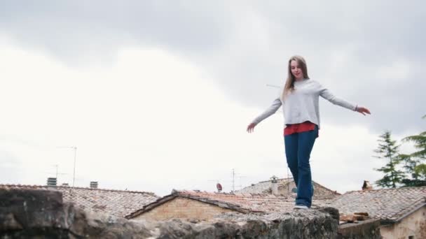 Jovem mulher caminha no telhado mantendo o equilíbrio com as mãos — Vídeo de Stock