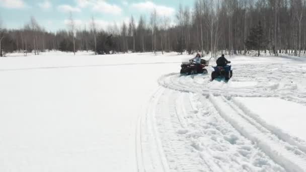 Mujer conduciendo una quad bike alrededor del hombre en el campo de nieve . — Vídeo de stock