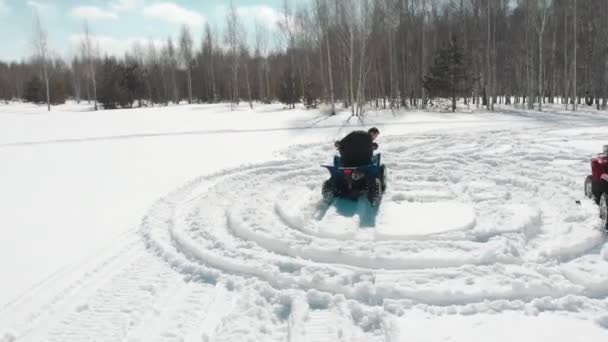 Homem e mulher dirigindo uma moto quad no inverno . — Vídeo de Stock