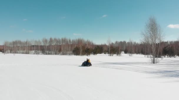 Un hombre cabalga con una mujer en un ATV. Nieve de invierno — Vídeo de stock