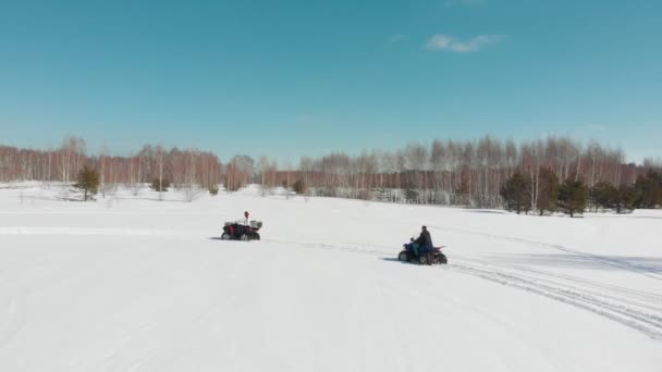 Egy férfi és egy nő lovagolni egy quad Bike keresztül a téli erdőben — Stock videók