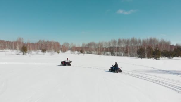 Чоловік і жінка їдуть на квадроциклі через зимовий ліс — стокове відео