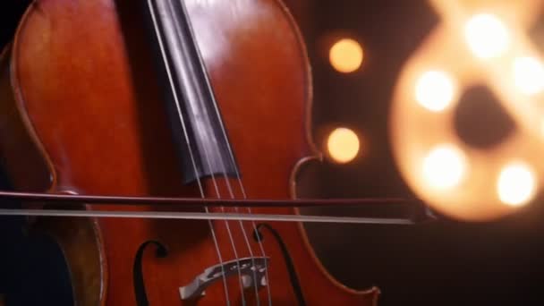 Une femme incline les cordes du violoncelle - debout près de la fenêtre — Video