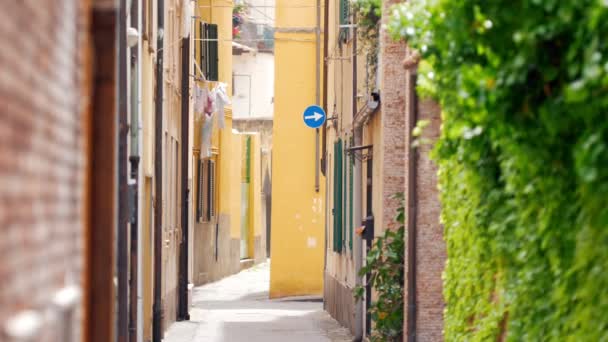 Blick auf eine enge Straße rechts eine grüne Wand links ein Balkon mit Wäscherei - typisch italienische Stadt — Stockvideo