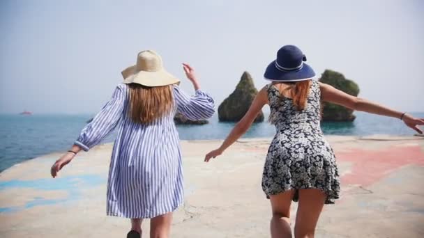 Zwei junge Frauen laufen die Promenade entlang direkt ans Wasser - Meer bei sonnigem Wetter — Stockvideo