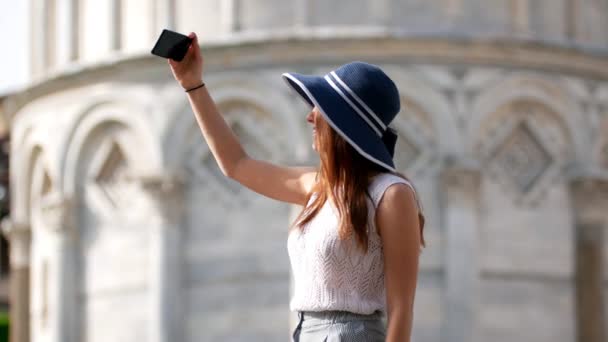 Mladá žena je fotografována na pozadí štíhlé věže — Stock video