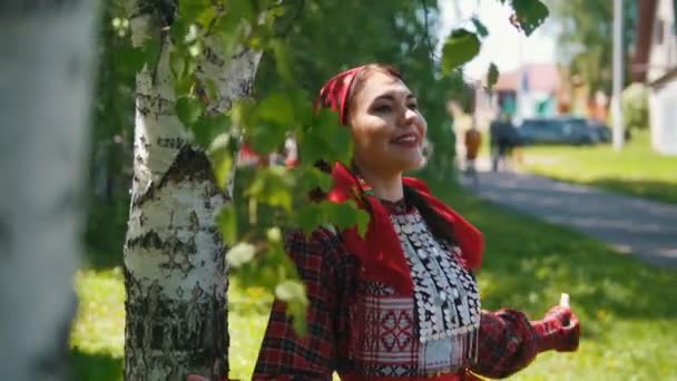 Jonge vrouwen in traditionele Russische jurk staan onder de berkenboom en zingen. — Stockvideo